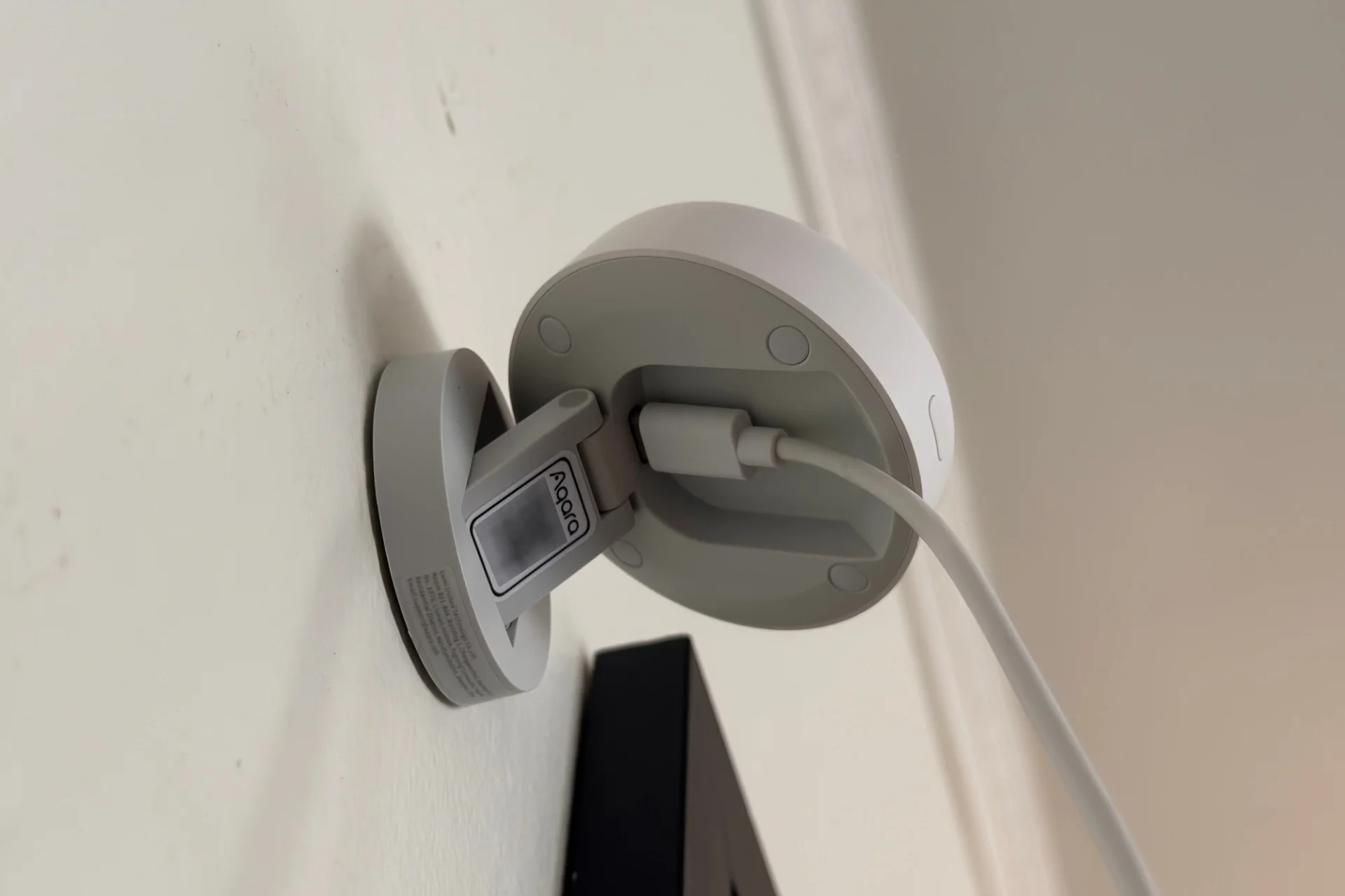 Aqara Fp400 pictured at partial extension with the main body tilted up, so that the QR code, which has been digitally blurred, and USB-C plug are visible. The USB-C plug and cable rest in a recessed cavity in the back of the main body.