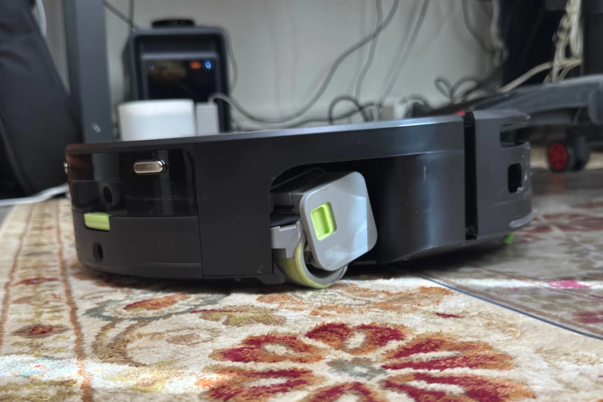 Roomba Max 775 pictured from the side, its mop roller visibly mopping a rug.